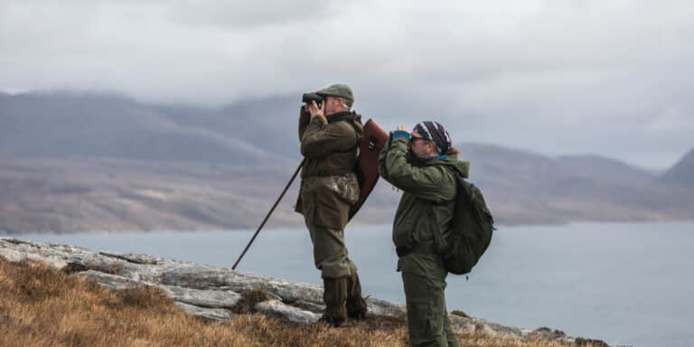 two men spying for deer with coastal backdrop