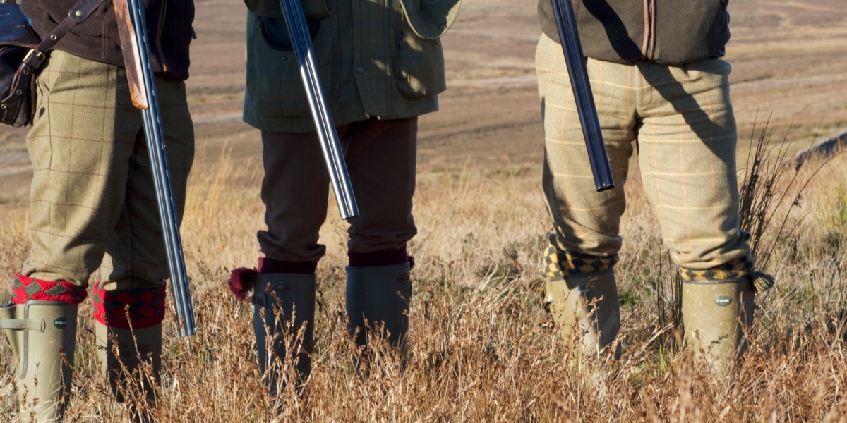 lower halves of three men with shotguns
