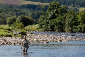 uomo guadare un fiume per la pesca del salmone in Scozia