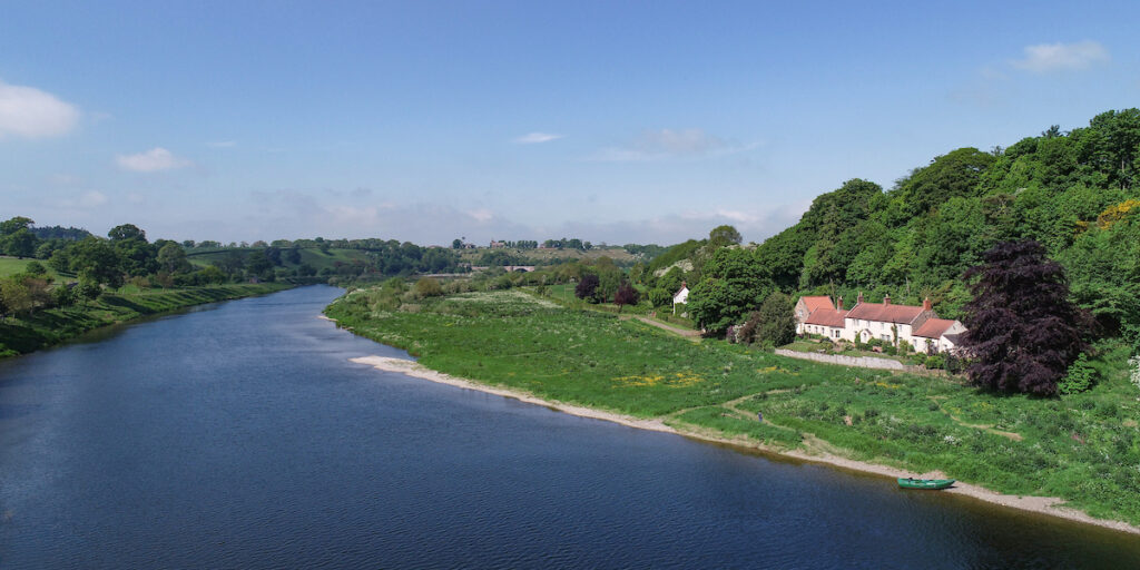 river tweed with green boat and riverside house