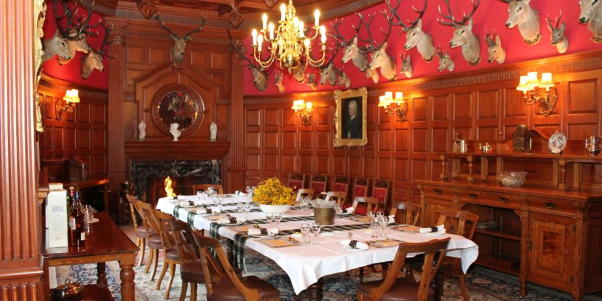 Scottish hunting lodge wood panelled dining room with stag heads