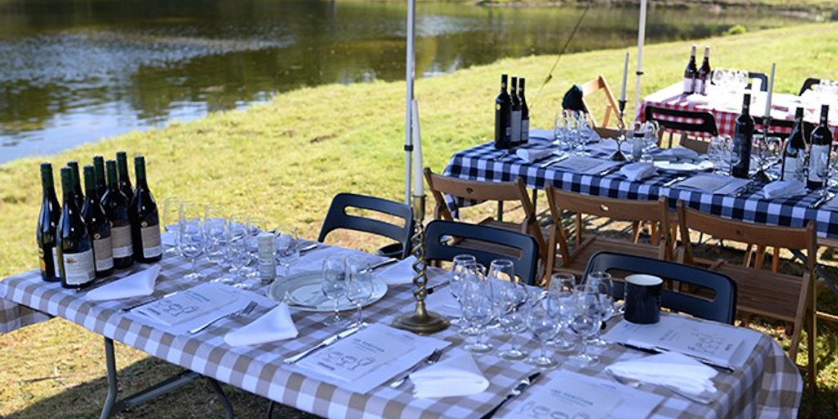 tables set for lunch under a gazebo by a river
