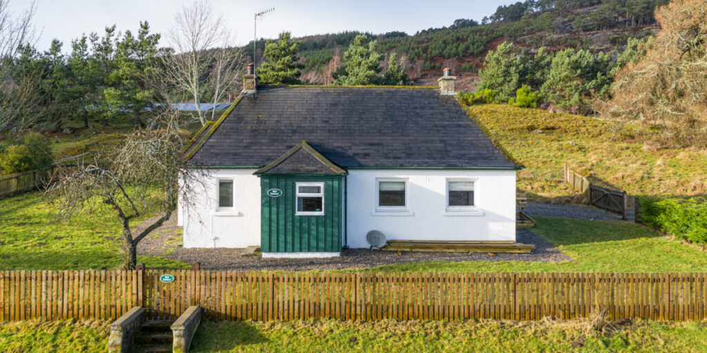 white washed Scottish cottage with green porch