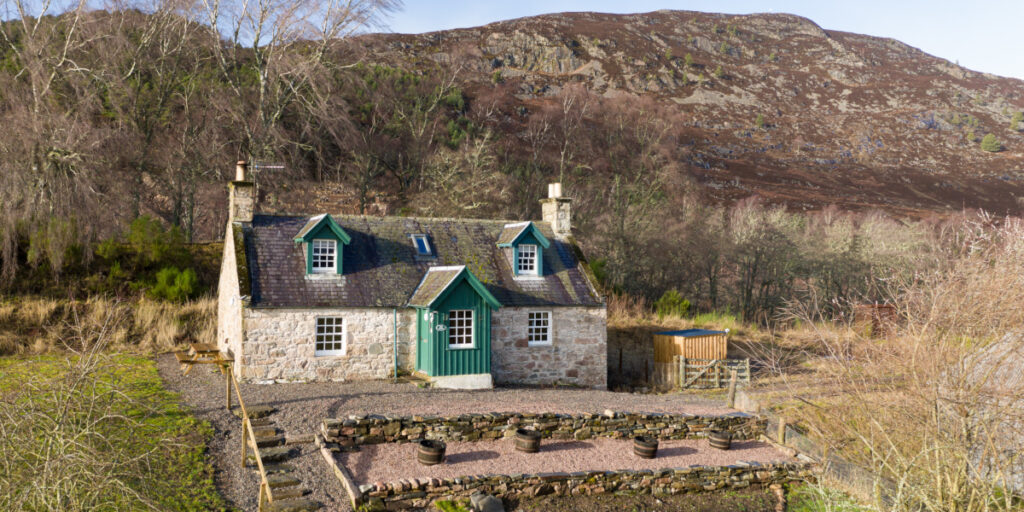 two storey Scottish stone built cottage with green woodwork