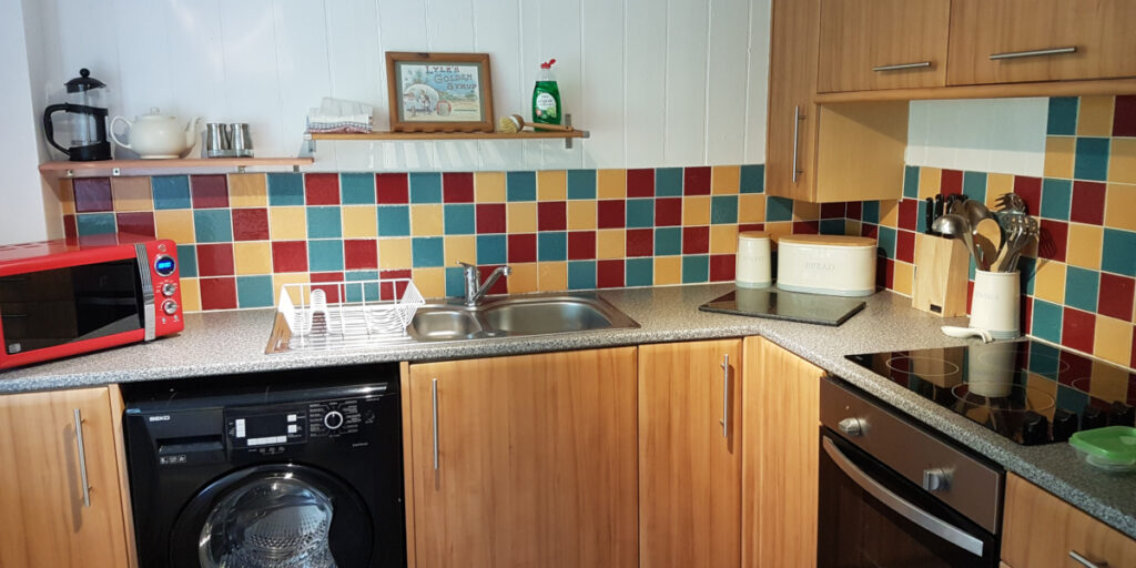 cottage kitchen with multi coloured tiles and stainless sink