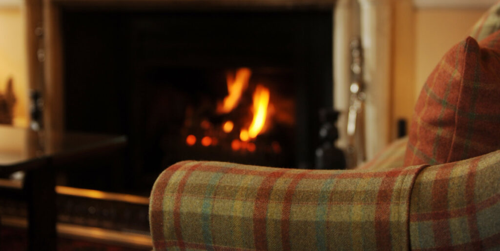 tartan fireside chair with lit open fire
