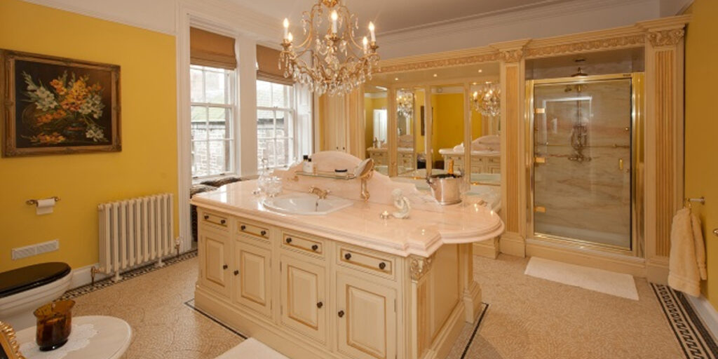 luxury fitted bathroom with cream units and chandelier