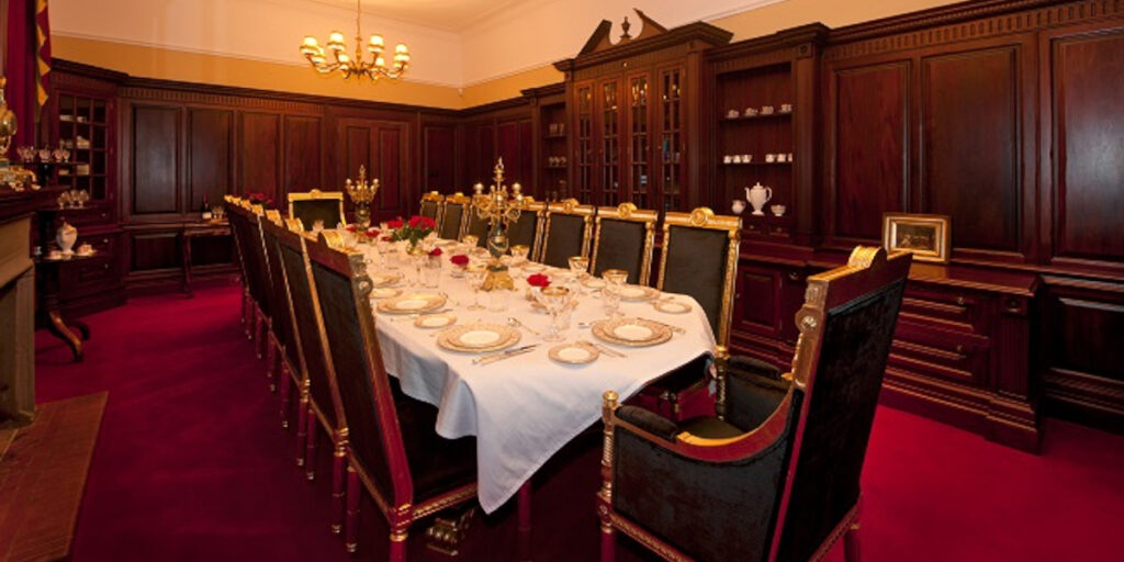 Wood panelled formal dining room with red carpet seating 16