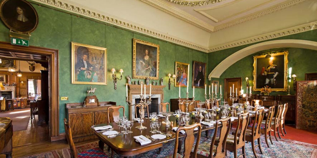 Scottish castle dining room with paintings on walls and candelabra on table