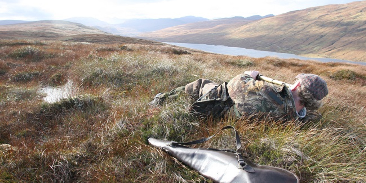 Scottish deer stalker prone spying deer