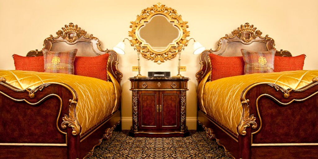 Luxury hotel room with twin beds and bedside cabinet, gold and orange linen