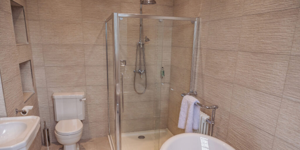 Shower and bathroom with beige tiling