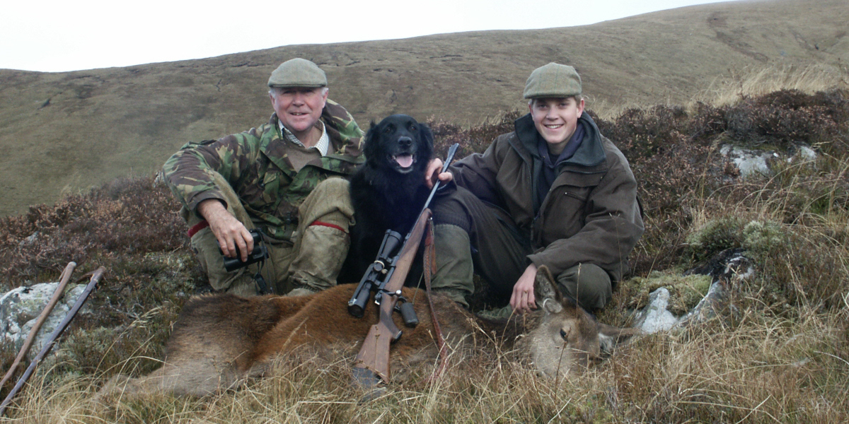 uomo ragazzo e cane con un fucile e un cervo