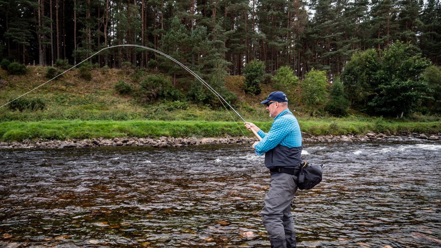 Angler playing an atlantic salmon river Dee Scotland with Twinpeakesflyfishing 2100x